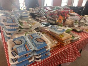 Tables filled with groceries prepared for a community food giveaway at Del Aire Baptist Church, including rice, canned goods, bread, and packaged foods.